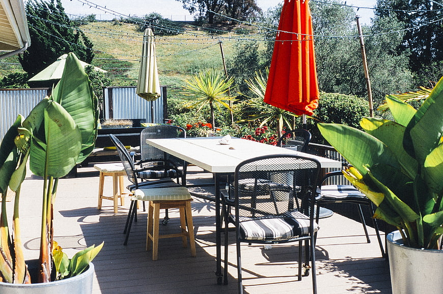 Sunny wooden deck with outdoor dining table and vibrant plants