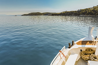 White yacht bow sailing on calm blue sea near coast