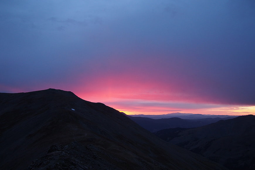 Dramatic Pink and Purple Sunset Over Mountain Silhouette