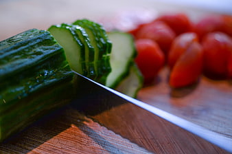 Sliced cucumber and tomatoes on wooden cutting board