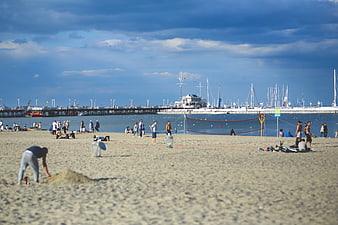 Busy Beach Scene with Pier, Marina, and Volleyball Net
