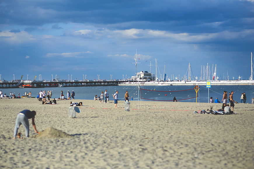 Busy Beach Scene with Pier, Marina, and Volleyball Net