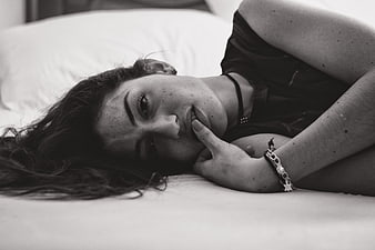 Black and white portrait of woman lying on bed