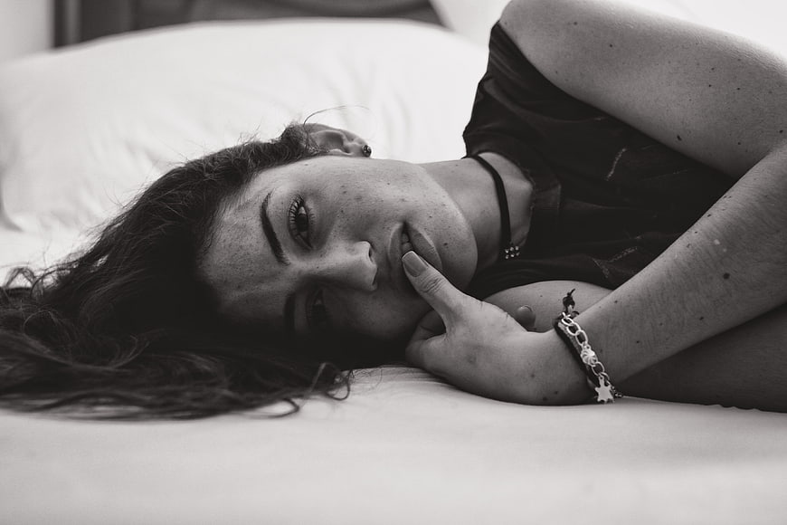 Black and white portrait of woman lying on bed