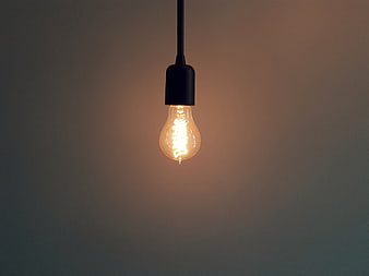 Glowing Edison Bulb Hanging Against Dark Background