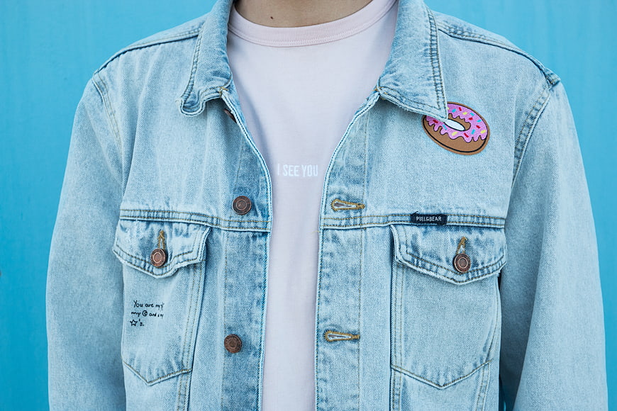 Close-up of light blue denim jacket with donut patch