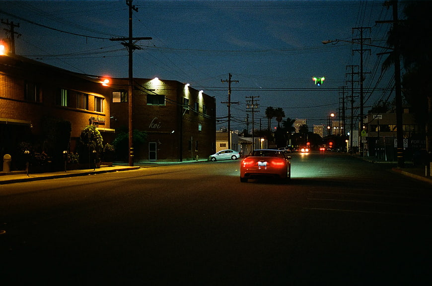Red Car Driving on City Street at Night