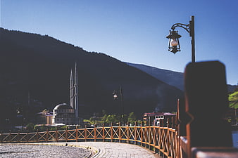 Mosque with minarets in mountain town with wooden bridge