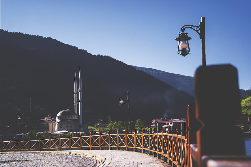 Mosque with minarets in mountain town with wooden bridge
