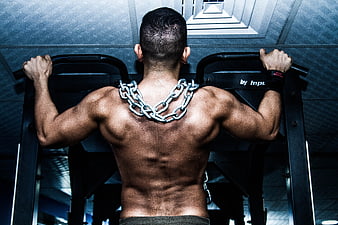 Muscular man back view with heavy chain necklace in gym