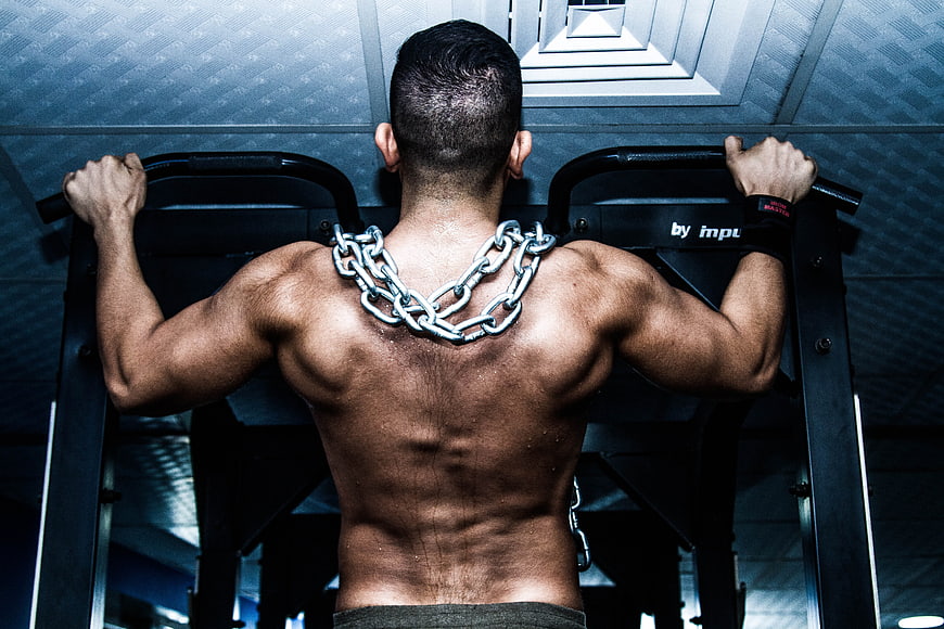 Muscular man back view with heavy chain necklace in gym