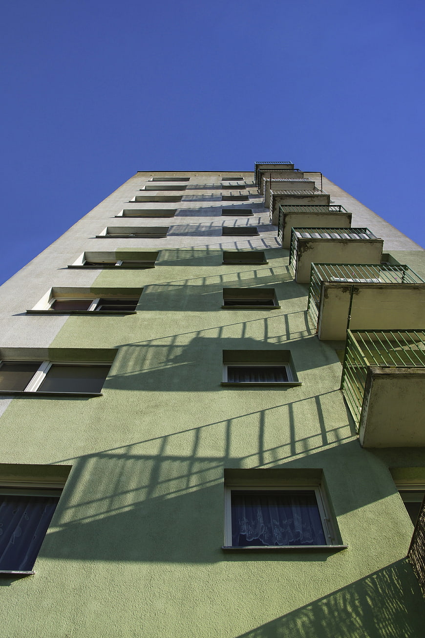 Low angle view of green apartment building with shadows