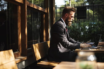 Bearded businessman working on laptop at outdoor cafe