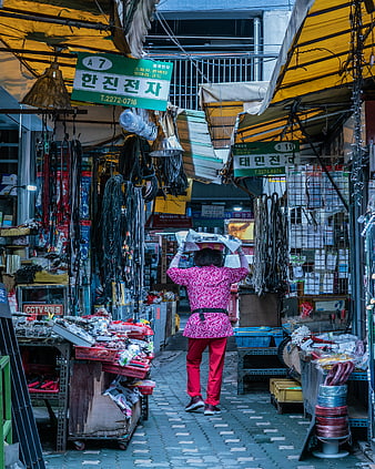 Woman carrying boxes in narrow Korean electronics market alley