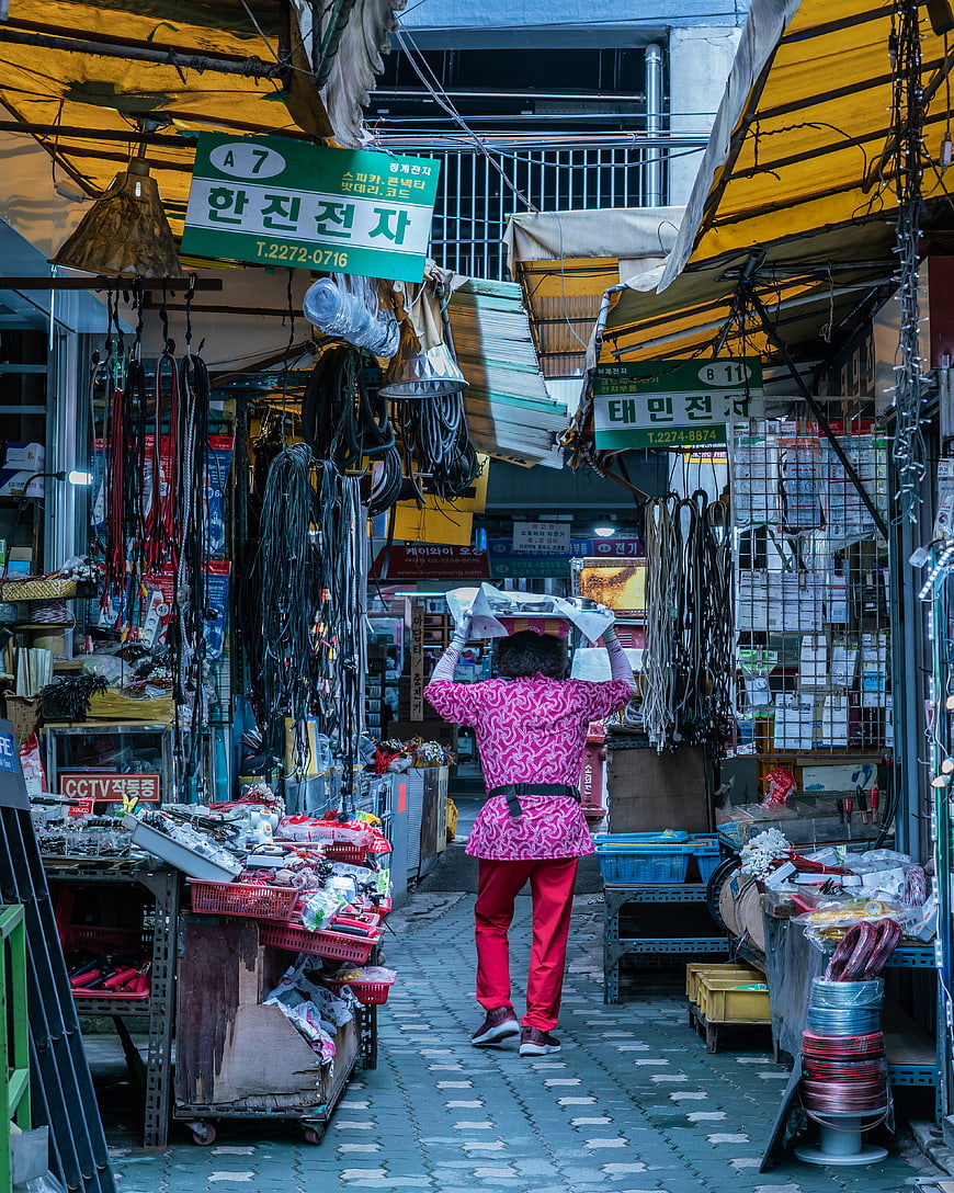 Woman carrying boxes in narrow Korean electronics market alley