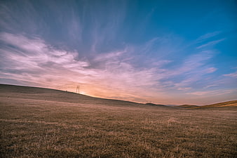 Golden Sunset Over Rolling Grassland Hills with Power Lines