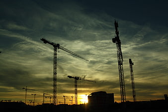 Construction Cranes Silhouette Against Dramatic Sunset Sky