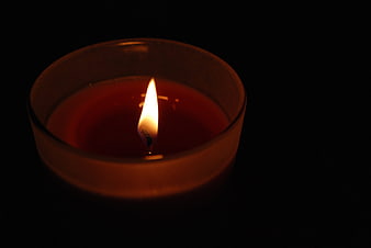 Red Candle Burning in Glass Holder on Black Background