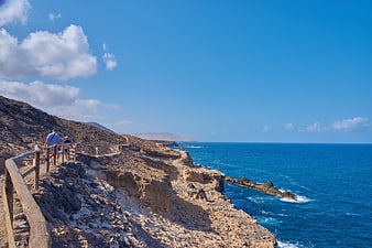 Hikers on Rocky Coastal Path with Blue Ocean View