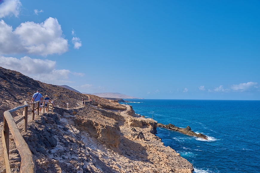 Hikers on Rocky Coastal Path with Blue Ocean View