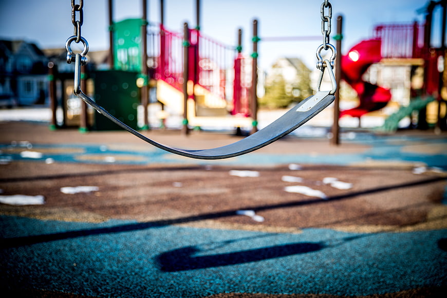 Empty metal swing at colorful playground with blurred background