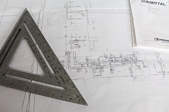 Architectural blueprints with metal speed square on white paper