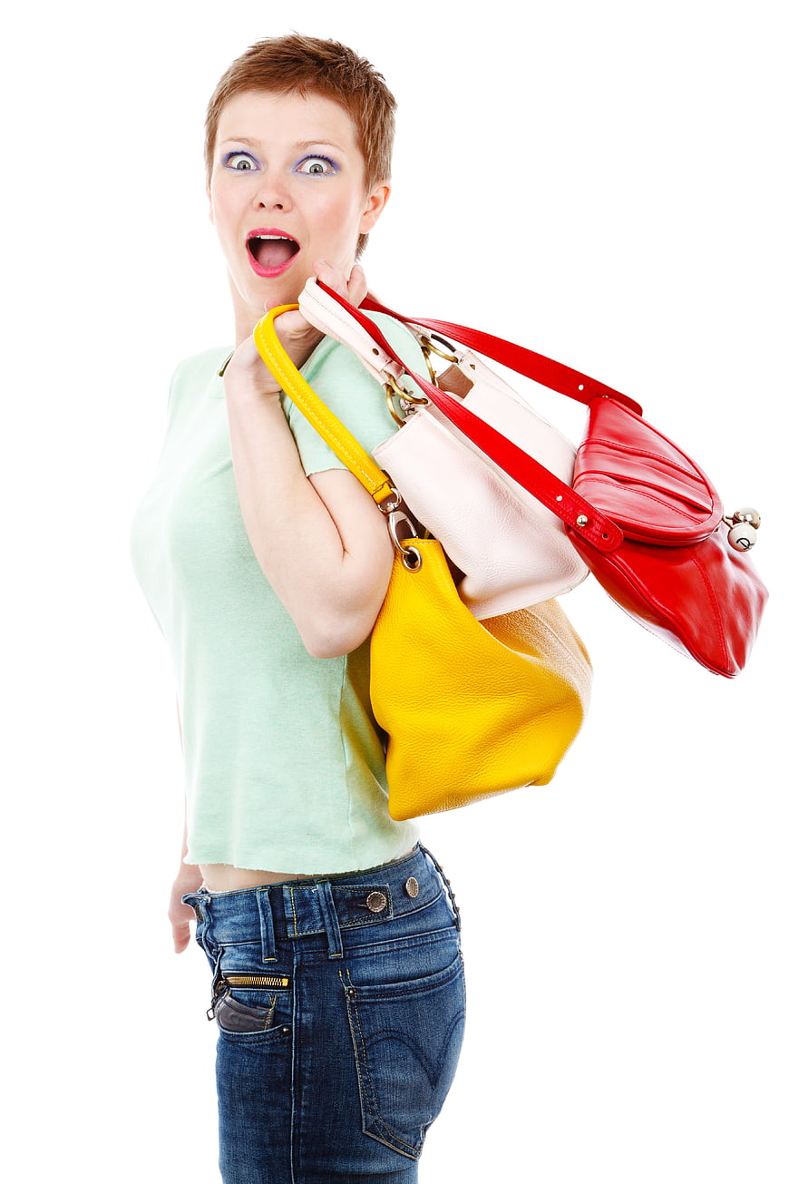 Surprised Woman Holding Multiple Colorful Handbags Against White Background
