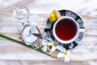 Overhead view of red tea, sugar jar, and pastry on wooden table