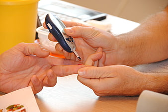 Close-up of hands performing blood glucose test with glucometer