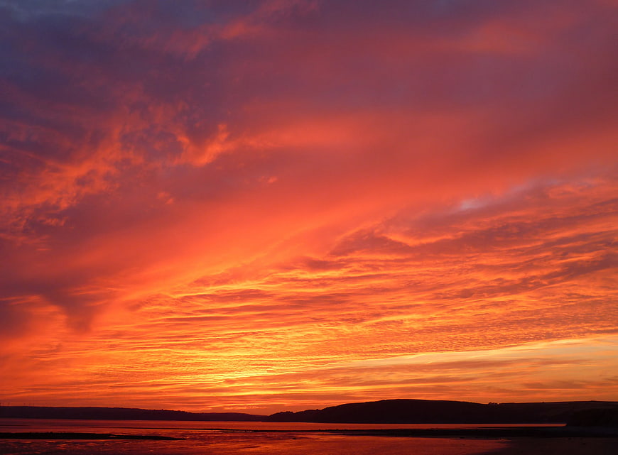 Vibrant Orange Sunset Over Coastal Hills and Ocean