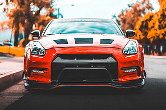 Front view of modified orange sports car on street