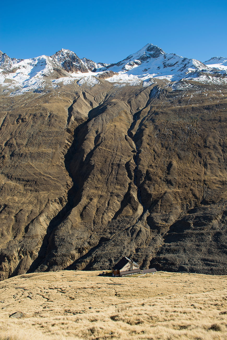 Lone Alpine Cabin in Snow-Capped Mountain Landscape