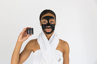 Woman with black face mask holding skincare jar