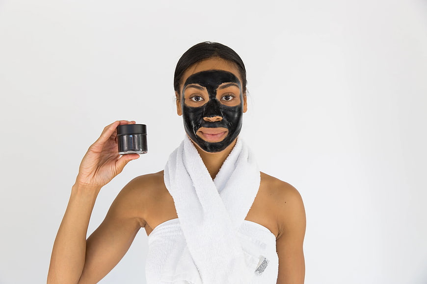 Woman with black face mask holding skincare jar