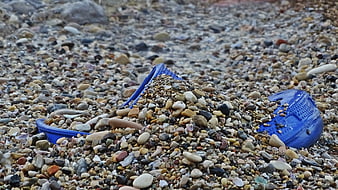 Blue plastic slipper buried in pebbles on a rocky beach