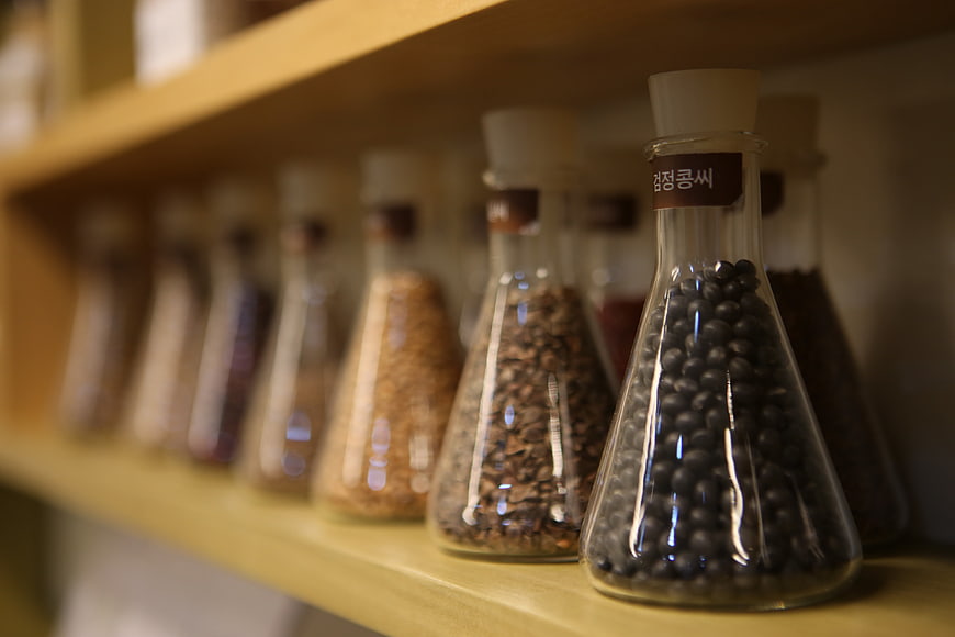 Glass bottles containing traditional oriental medicine herbs on a wooden shelf