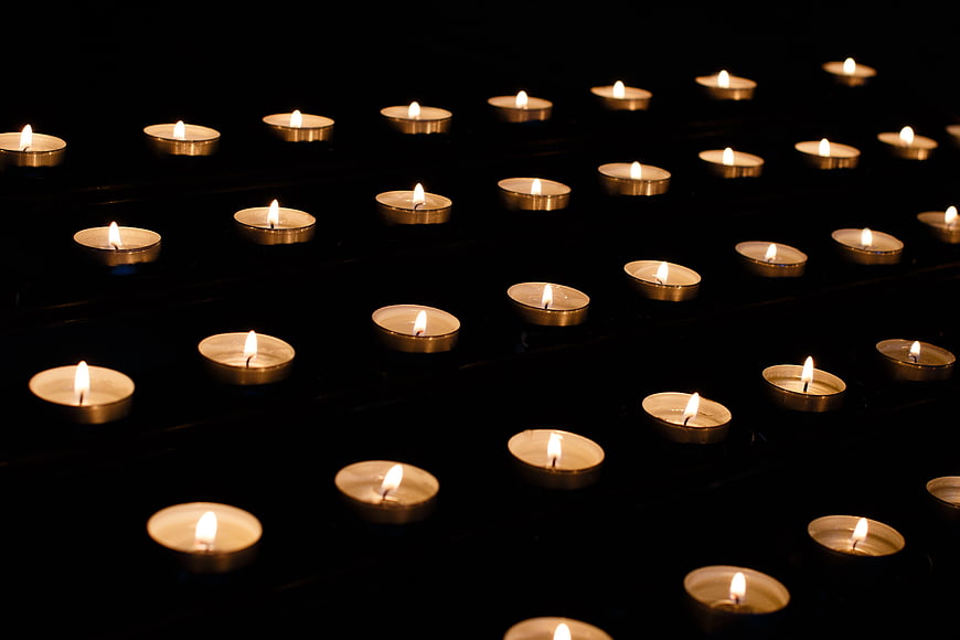 Rows of lit memorial candles glowing in the dark