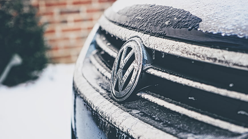 Close-up of Volkswagen car grille covered in winter snow and ice