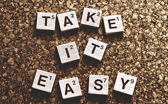 Scrabble tiles spelling take it easy on cork background