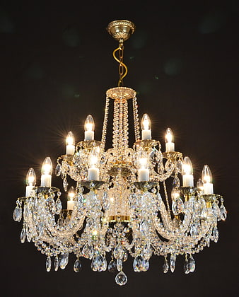 Illuminated Crystal Chandelier With Gold Accents Against Dark Background