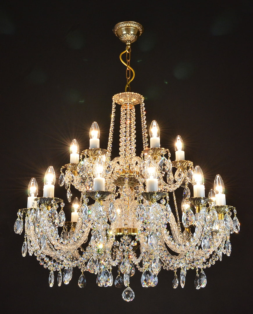 Illuminated Crystal Chandelier With Gold Accents Against Dark Background