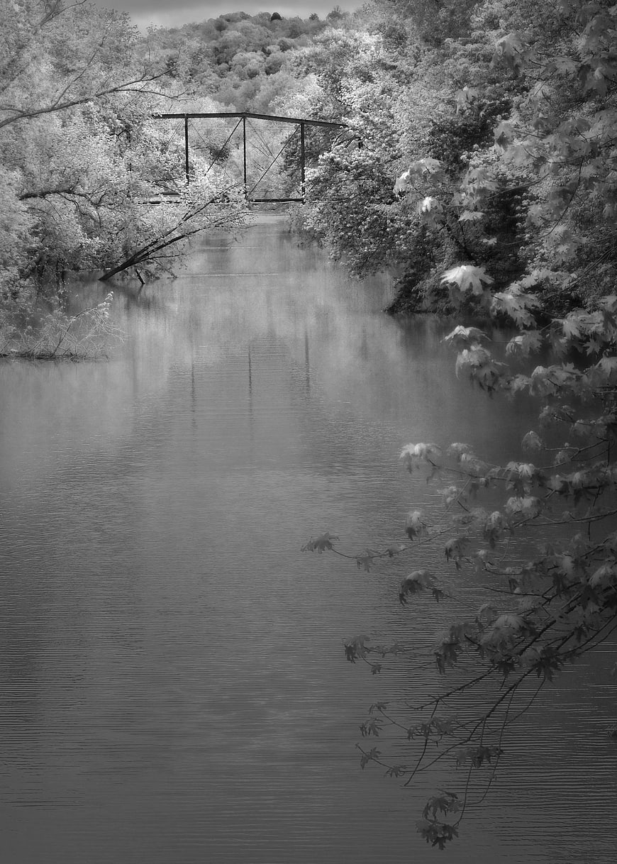 Black and white infrared landscape of a bridge over a river