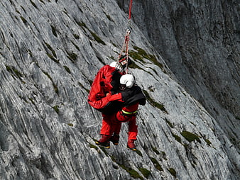 Mountain Rescue Team Rappelling Down Steep Grey Cliff Face