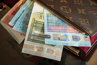 Euro banknotes spilling from a luxury designer wallet