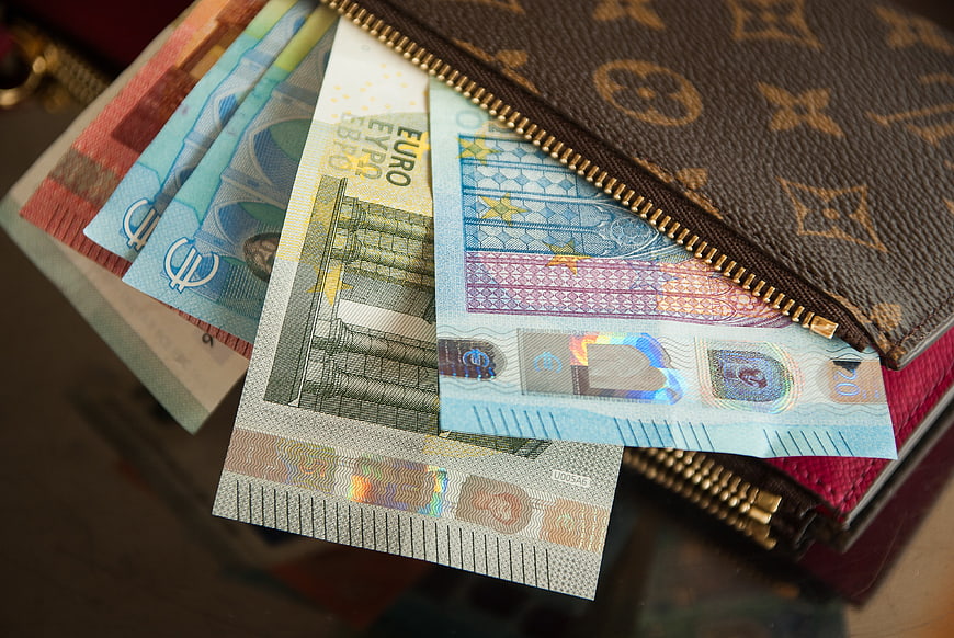 Euro banknotes spilling from a luxury designer wallet