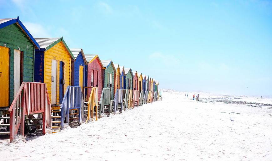 Colorful Beach Huts on White Sand Under Blue Sky