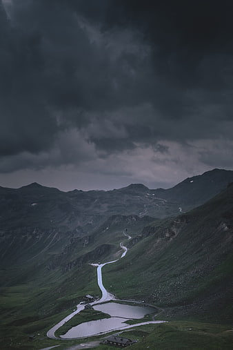 Dramatic Winding Mountain Road Under Stormy Sky