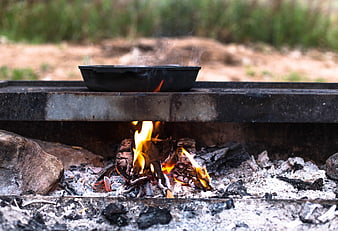 Camping cooking with cast iron skillet over open fire