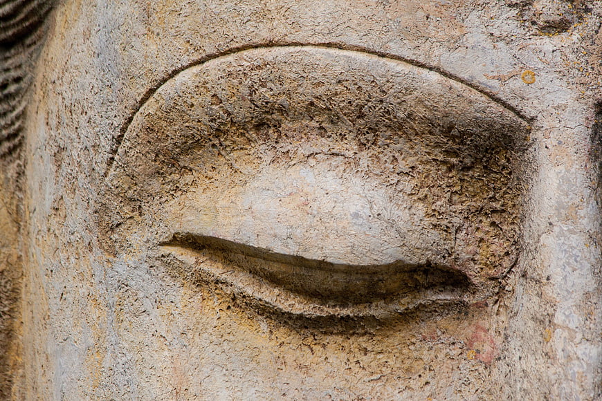 Close-up of weathered stone Buddha statue eye detail
