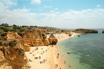 Sunny coastal beach with golden cliffs and turquoise water